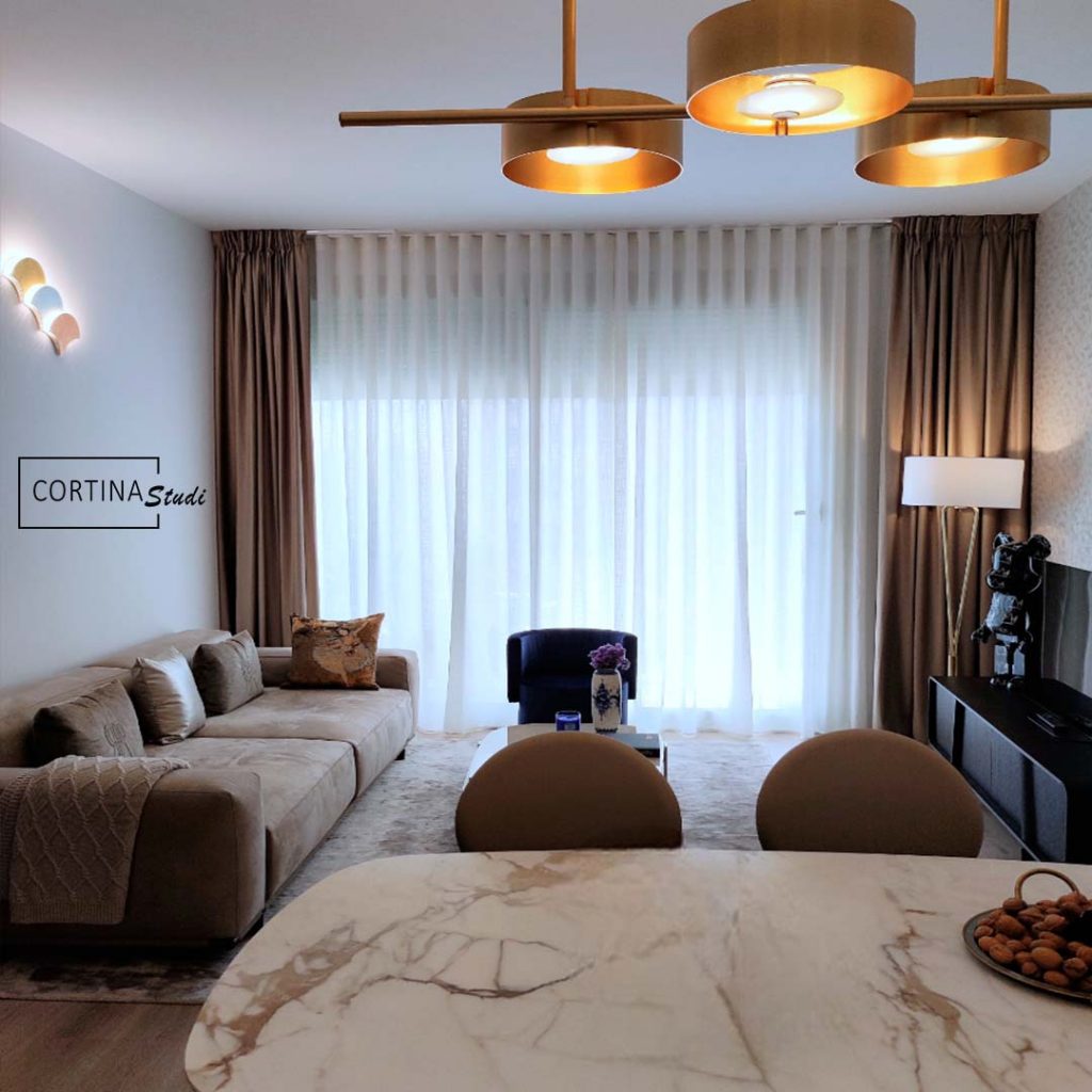 Las cortinas de este salón de un piso en Barcelona, son la elección perfecta para un salón de estilo clásico moderno, las telas de las cortinas están pensadas para graduar la visibilidad y la luz, por un lado unas cortinas confeccionadas a onda perfecta en una tala de lino transparente, por otro lado, las cortinas gruesas, son de terciopelo en color beige tostado, la elección de colores neutros en cortinas es muy recomendable para combinar bien todos los elementos decorativos, en cortinastudi, la tiende de cortinas de referencia en Barcelona, te dan ideas, confeccionas e instalan cualquier tipo de cortinas a medida