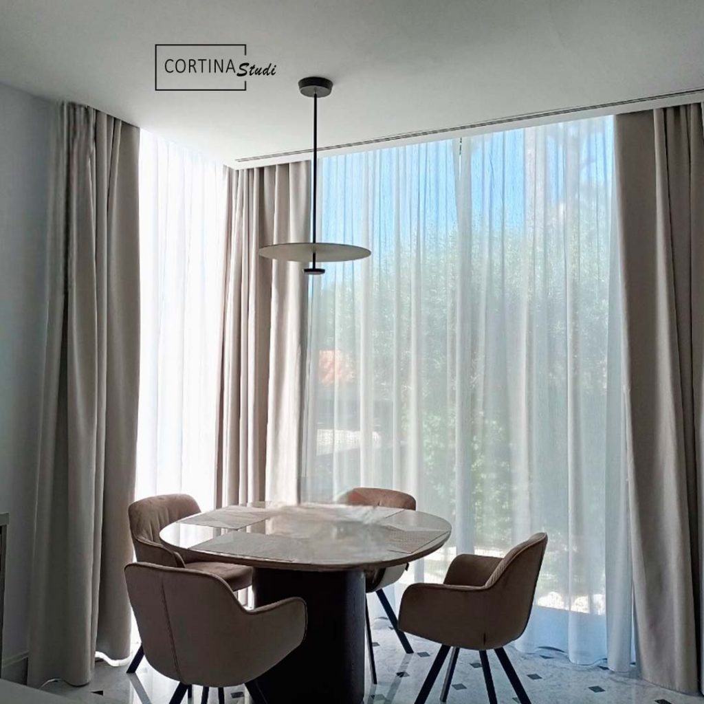 Pequeño comedor con unas cortinas dobles hechas a medidas por cortinastudi, las cortinas transparentes son unos visillos de lino en color blanco y las cortinas dobles es una tela opaca para cortinas, las cortinas opacas tienen una apariencia textil que consigue crear una atmosfera acogedora, en Cortinastudi puedes encontrar cualquier tipo de cortinas hechas a medida es la mejor tienda de cortinas de Barcelona