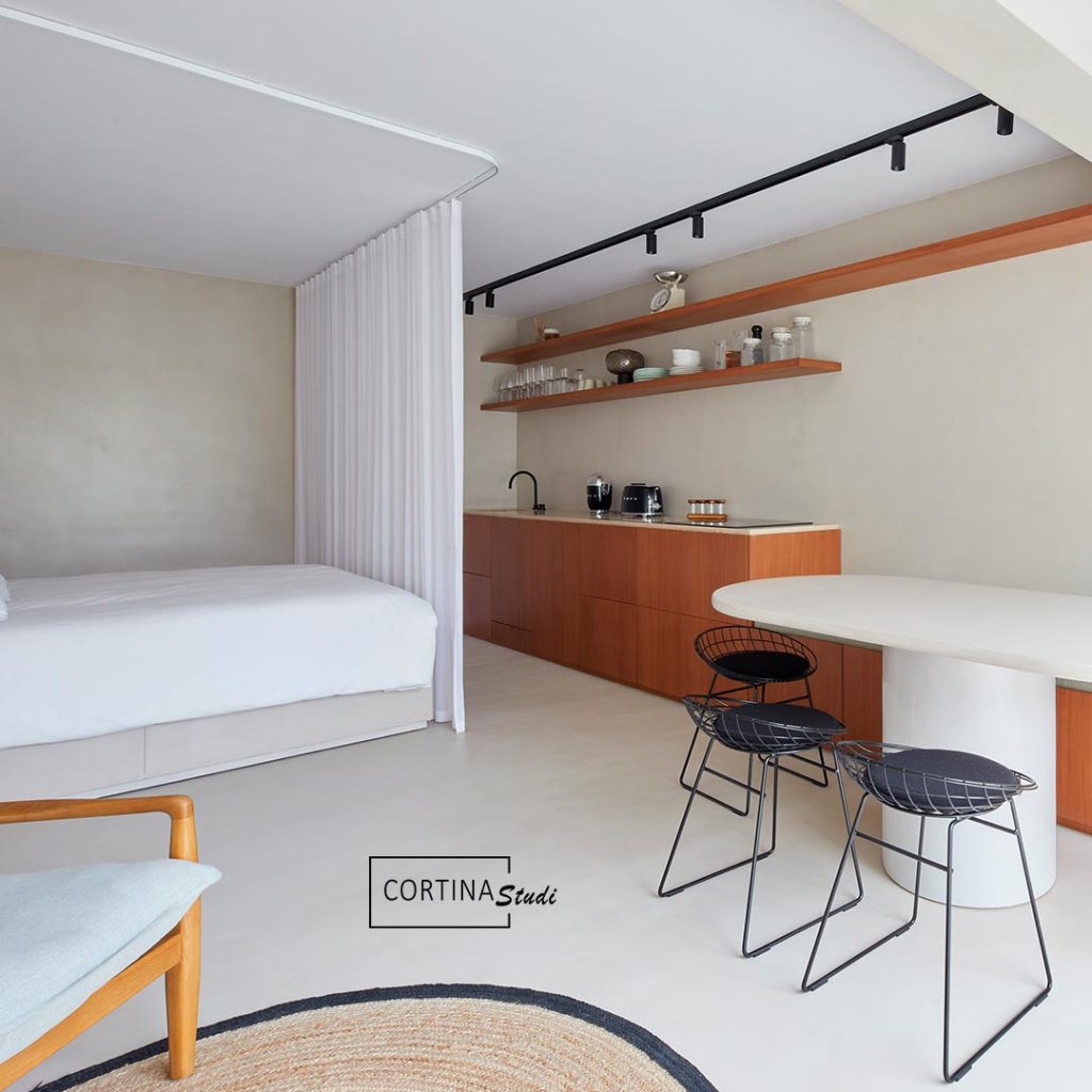 Rieles curvos a medida para cortinas para separar espacios, el riel está instalado en el techo y es de aluminio blanco para que se integre en el espacio sin llamar la atención. los rieles permiten hacer formas curvadas para que la tela de las cortinas se desplace a lo largo de toda la longitud del riel a voluntad. La instalación de estas cortinas de onda perfecta la ha hecho CortinaStudi y son unas cortinas modernas de lino en blanco que separan el espacio de la cocina haciendo a la vez la función de cortinas de dormitorio